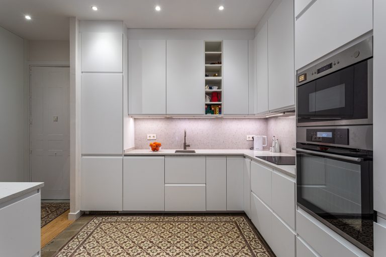 Vista de amplia cocina con muebles a medida de color blanco abierta a recibidor