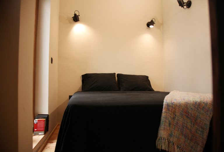 Dormitorio con cama y apliques de estilo industrial y puerta de salida a la terraza
