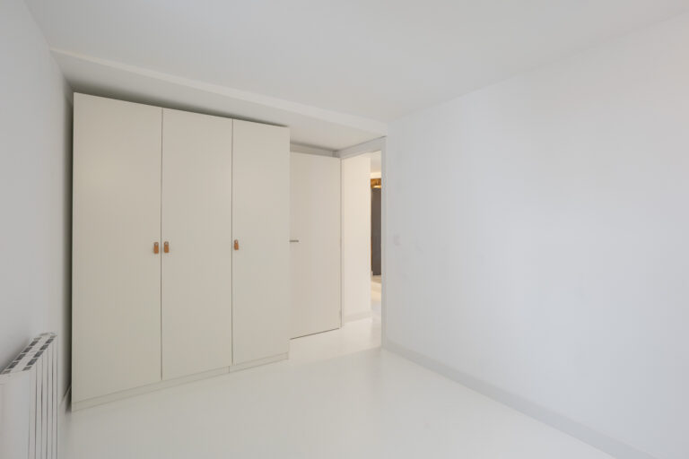 habitación totalmente blanca, con radiador suspendido en la pared.